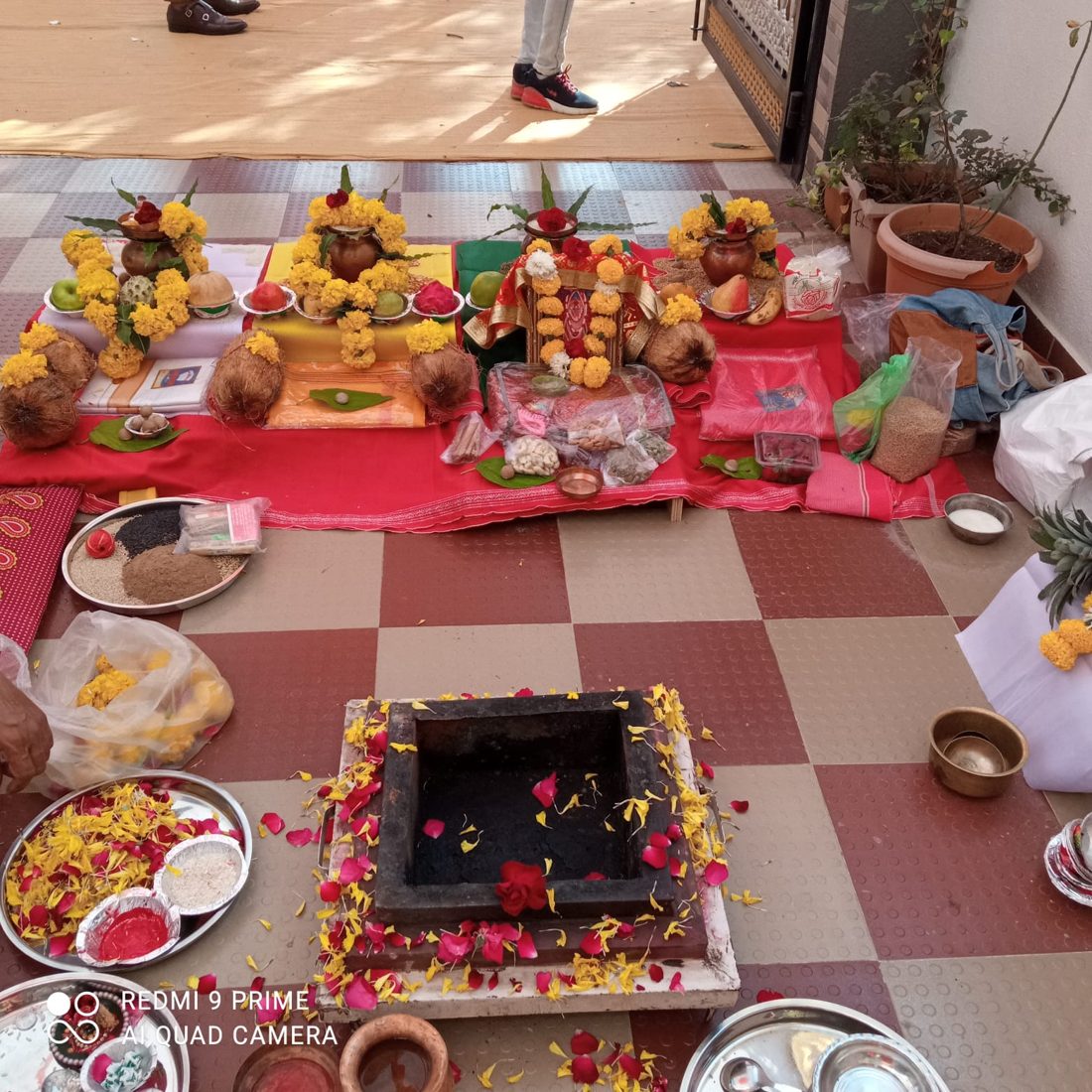 Puja setup with decorated kalash, coconuts, fruits and a havan kund