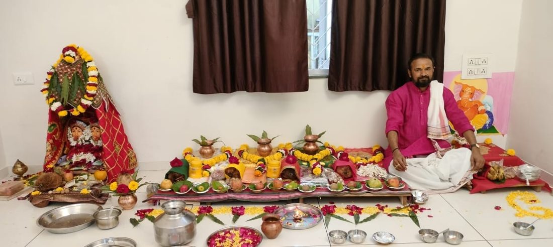 Large flower-decorated puja arrangement with a Devi mandap and offerings