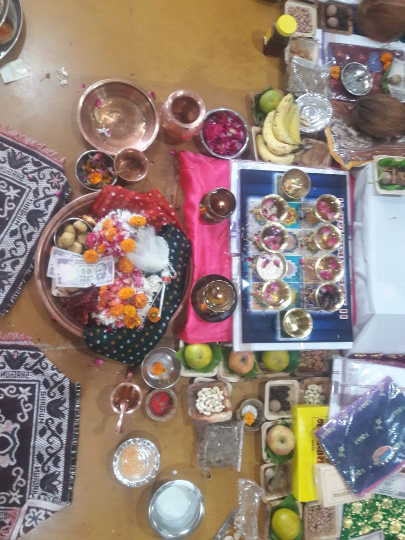 Top view of puja items: copper vessels, flowers, fruits and dry fruits