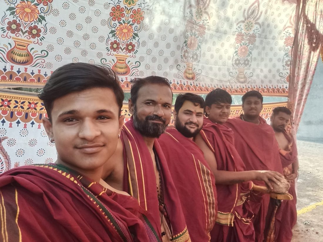 Group of priests wearing maroon shawls before a printed backdrop