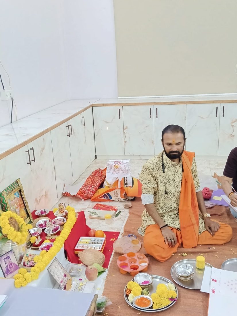 Priest performing a puja with marigold garlands and a deity frame