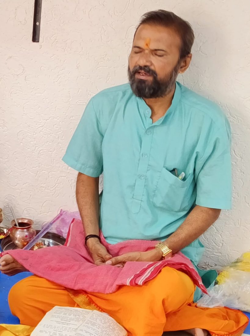 Priest chanting mantras with eyes closed during a puja
