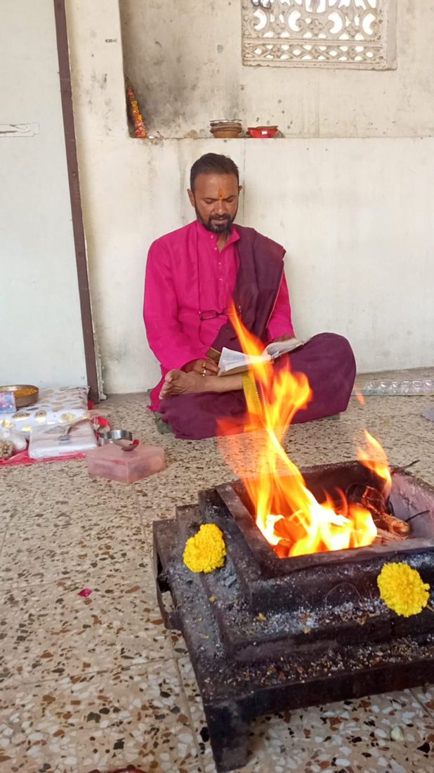 Priest reading mantras beside a havan fire