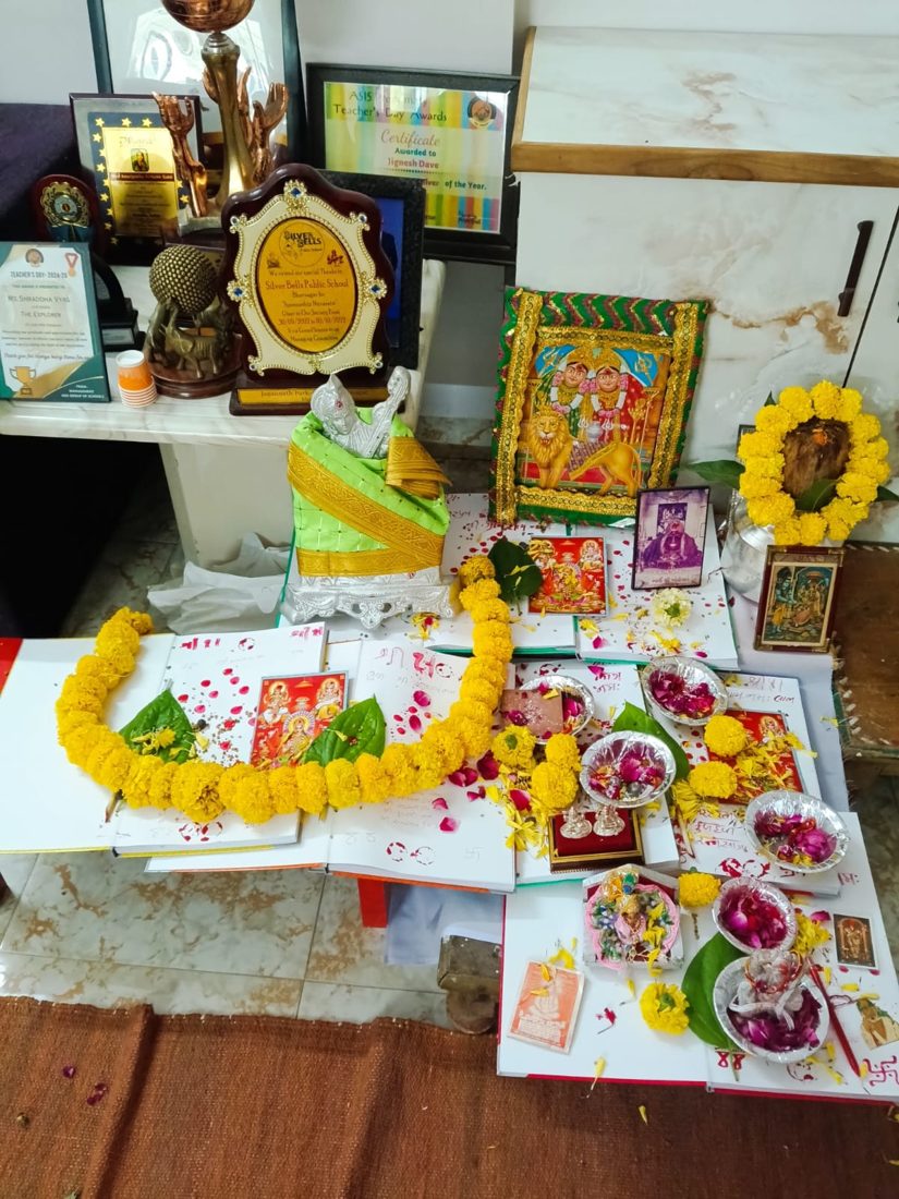 Puja arrangement with a marigold garland, deity pictures and flower petals