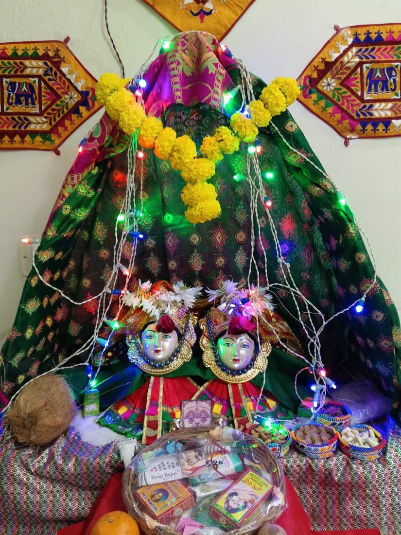 Decorated deity mandap with colourful lights, marigold garland and an offering basket